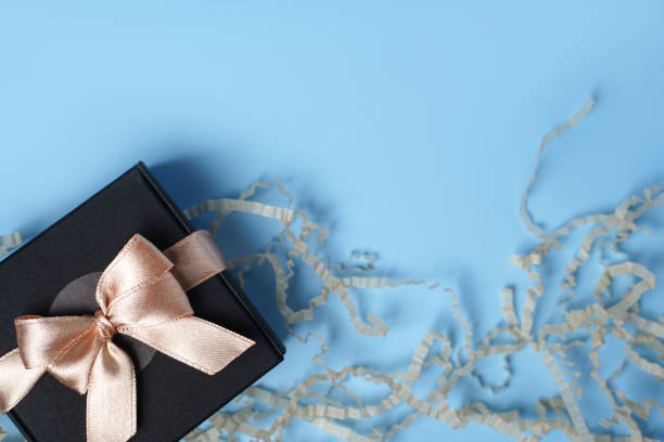istock Gift present or gift box and paper confetti on a blue table background from above. Flat composition. Greeting card for birthday, mothers day or wedding. 1366562720