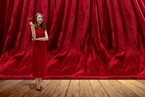 Asian Chinese woman in a cheongsam dress holding red envelopes. Happy Chinese New Year