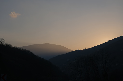 Sunset of winter day, huge mountains, silhouette of mountains and sun.