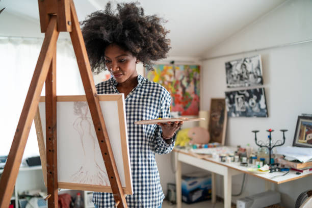 istock Afro female fine artist  drawing in studio on a canvas, placed on a tripod 1366564467