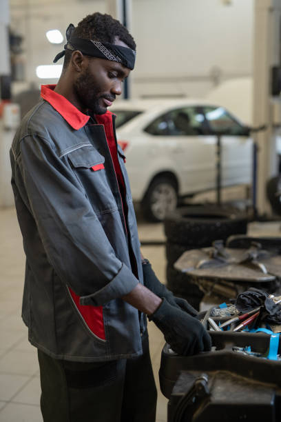 istock Gloved African repairman or technician in workwear taking handtool 1366565947