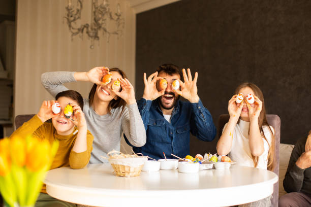 istock A family is having fun, smiling and holding Easter eggs near their eyes. 1366566202