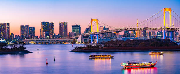 Aerial Skyline of Rainbow Bridge and Symbolic Tokyo Tower with Twilight Sky at Blue Hour in the evening with a few lighten boats in the river. Aerial Skyline of Rainbow Bridge and Symbolic Tokyo Tower with Twilight Sky at Blue Hour in the evening with a few lighten boats in the river. tokyo prefecture tokyo tower japan night stock pictures, royalty-free photos & images