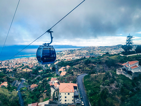 Cable car from the seaside to Monte in Funchal, Madeira Island Portugal with a lovely aerial view over the city and sea. Tourists take this way of transport for the views over the city and to visit the botanical gardens in Monte as well as the tradional toboggan ride down the hill.