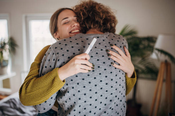 pareja joven y feliz abrazándose porque la prueba de embarazo es positiva. - prueba de embarazo fotografías e imágenes de stock