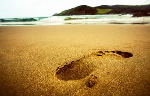 Walking on sand. Tracking person trail marks background.