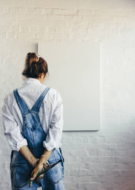 istock Pensive female painter standing in front of a blank canvas 1366572957