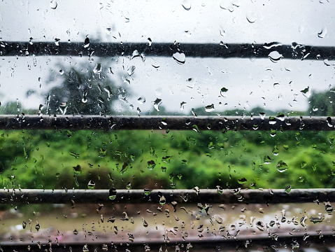A Closeup image of water droplets on the window of running train during rain