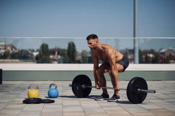 Sportsman doing exercise with barbell outdoors stock photo