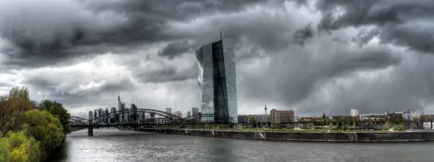 Panoramic view of the ECB (European Central Bank) in Frankfurt am Main with the river Main in the foreground during stormy thunderstorms and dramatic cloudy skies

(All logos and legal identifiers are removed as you requestet)