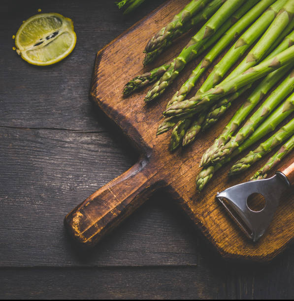 Fresh green asparagus with lemon on a vintage wooden cutting board stock photo