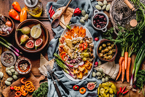 Tasty Mediterranean cuisine with healthy food with hummus plate. Various pickled and fresh  vegetables: olives, figs, green almond. Vegan party food Top view. Festive gathering