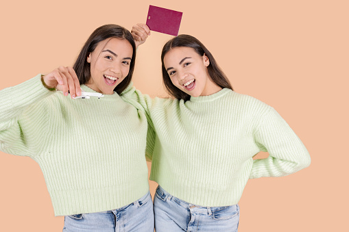 women sisters twins, with passport and plane happy travel concept