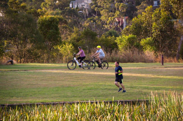 istock People riding Electric Bikes and Running through Park 1366576555