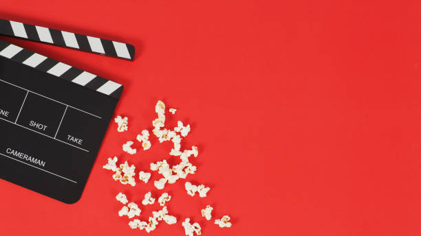 istock Black Clapper board or movie slate and popcorn on a red background.  New 1366577142