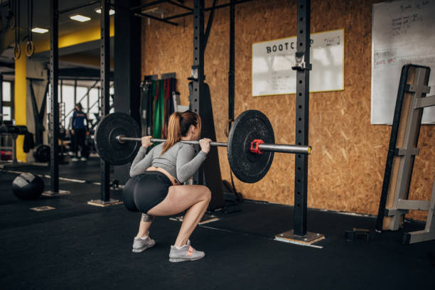 mulher se exercitando com pesos na academia - crouching exercising women barbell - fotografias e filmes do acervo