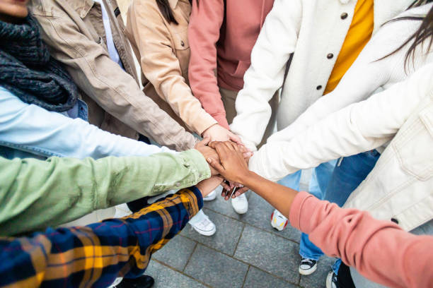 istock Young people stacking hands in city street 1366579389