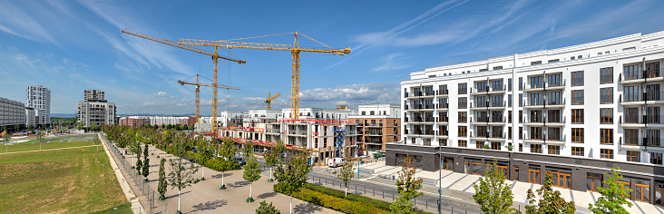 A new development area of residential buildings with construction cranes and construction site in the background\n\n(All logos and legal identifiers are removed as you requestet)