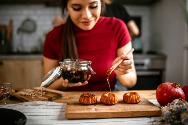 Woman pouring honey on delicous doughnut muffins.