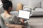 Woman using laptop computer on sofa, white blank empty screen mock-up