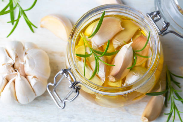 aglio fresco e olio all'aglio su sfondo di legno - garlic cooking oil cutting board horizontal foto e immagini stock