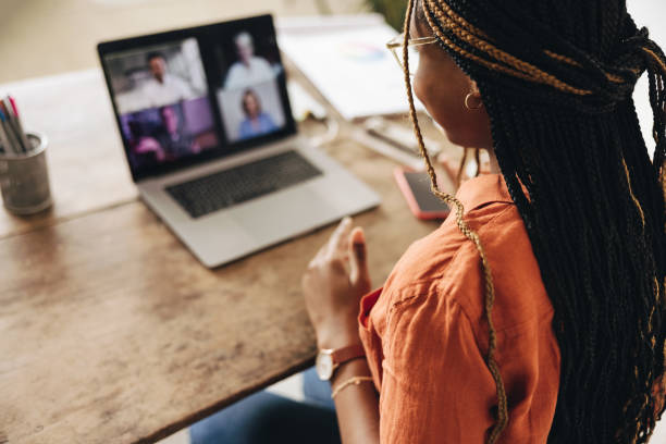 Graphic designer attending a virtual meeting at her desk Graphic designer attending a virtual meeting with her clients. Creative female freelancer using a laptop for a video call. Young woman working on a new project in her home office. conference call stock pictures, royalty-free photos & images