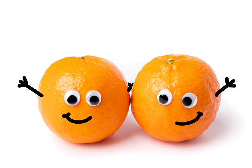 A humorous image of a couple of oranges with googly eyes and drawn on smiles and hands.