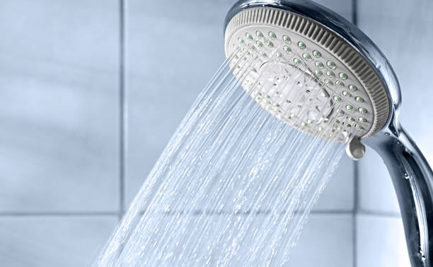 istock Shower head and water stream in blue bathroom 1366586373