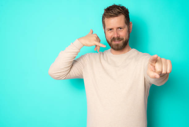 istock Young bearded man making call me gesture standing isolated over green background. 1366587922