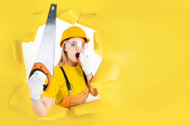 istock Woman in protective helmet is holding manual saw 1366587935