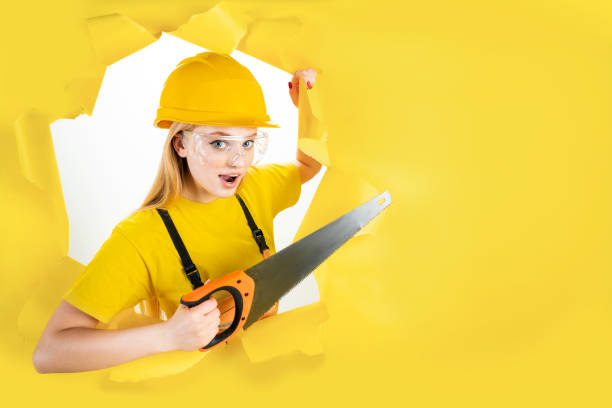 istock Woman in protective helmet is holding manual saw 1366588361