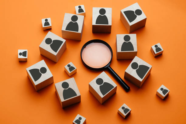 cubos de madeira com a imagem de um homem estão ao lado de uma lupa em um fundo laranja. o conceito de busca de talentos ou pesquisa de conceito de funcionário usando uma lupa. - human resources recruitment occupation magnifying glass - fotografias e filmes do acervo