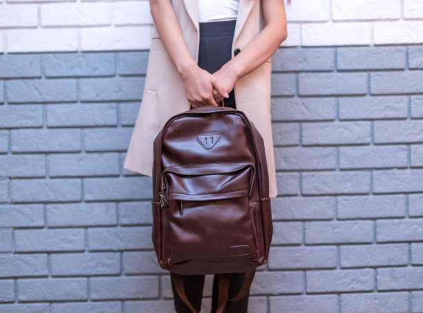 Woman holding brown leather backpack in the hand