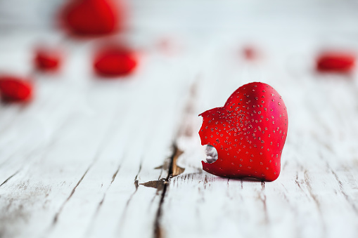 Valentines Day broken glass heart. Selective focus with extreme blurred foreground and background over a wooden table.