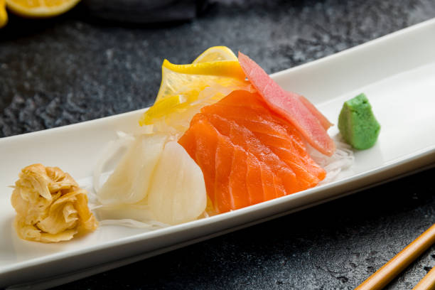 istock Sashimi salmon, tuna and scallop on a plate on dark stone table 1366595060