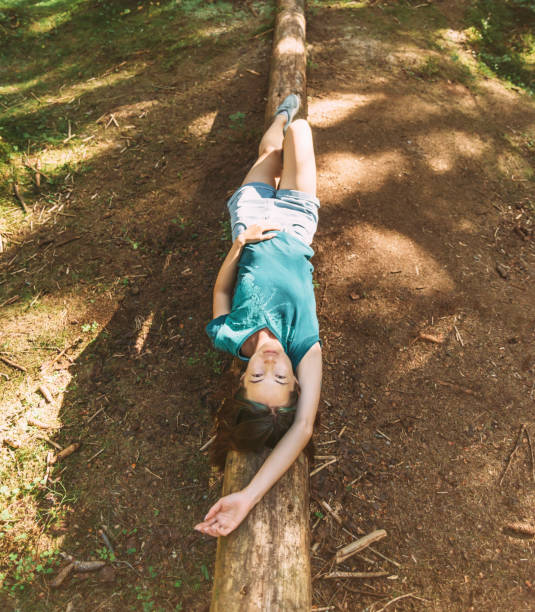 istock Beautiful woman lying on fallen tree trunk, looking at camera. 1366595542