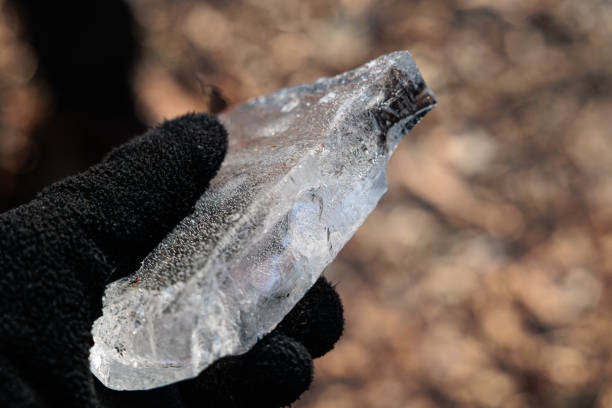 close up view of a hand covered with a black winter glove, holding a thick ice block