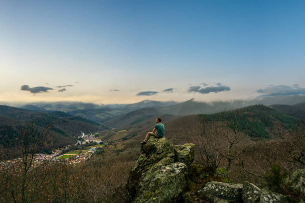 istock Man standing on top of rock in low mountain range landscape 1366596791
