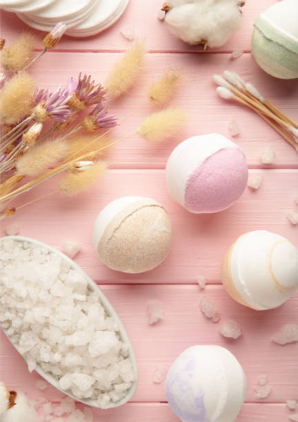 istock Aroma bath bombs in spa composition with dry flowers and salt on pink background. Vertical photo. 1366598666