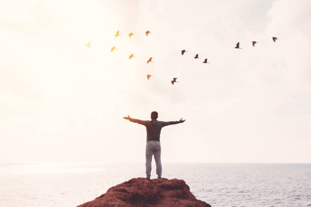istock Happy backpack man raise hand up and birds flying on sunset sky at river background. 1366598849