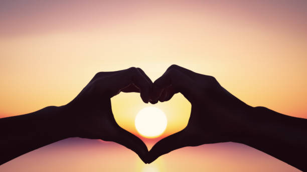 istock Man hands heart shape on sunset sky at tropical beach abstract background. 1366598929