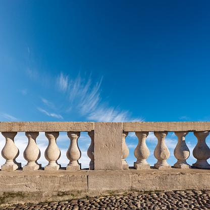 Close-up of a white marble balustrade in classical style against a blue sky with clouds and copy space. Vicenza, Veneto, Italy, Europe.