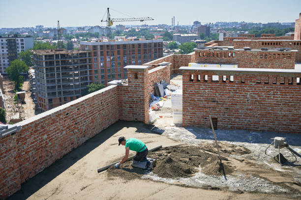 istock Male worker screeding floor outdoors at construction site. 1366599736