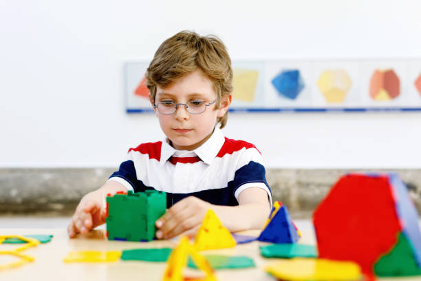 istock Happy kid boy with glasses having fun with building and creating geometric figures, learning mathematics and geometry 1366599852