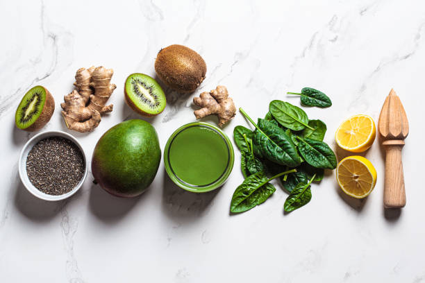 Green spinach and mango smoothie with ingredients on white marble background. Detox drinks concept.