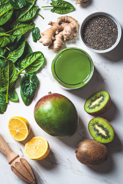 istock Green spinach and mango smoothie with ingredients on white marble background. Detox drinks concept. 1366600113