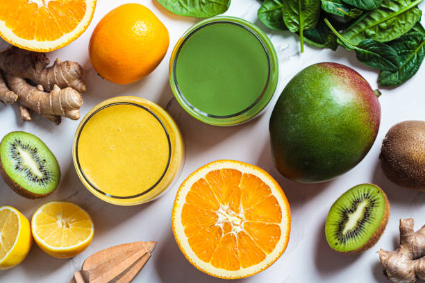 Yellow mango smoothie and green spinach smoothie with ingredients on white background. Detox drinks concept. Yellow mango smoothie and green spinach smoothie in glasses with ingredients on white marble background, close-up. Detox drinks concept. juice bar stock pictures, royalty-free photos & images