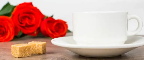 red roses and coffee cup on wooden table, love or romantic good morning concept