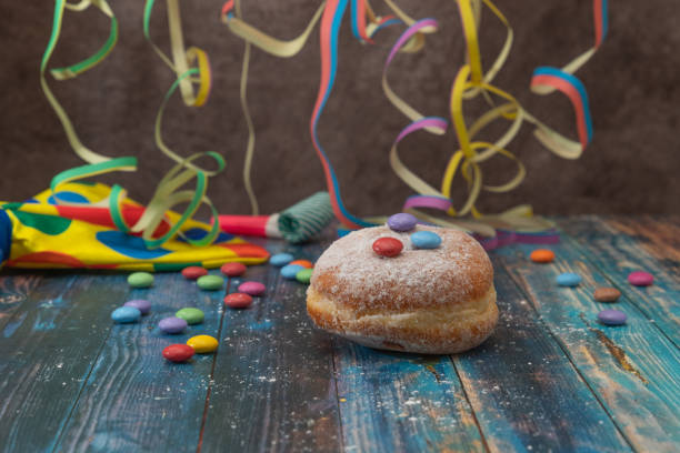 Sweet Doughnut, Krapfen or Berliner with streamer and decoration on a blue wooden table Berliner, Krapfen, doughnut are traditional sweet food for carnival, focus on foreground fastnacht stock pictures, royalty-free photos & images