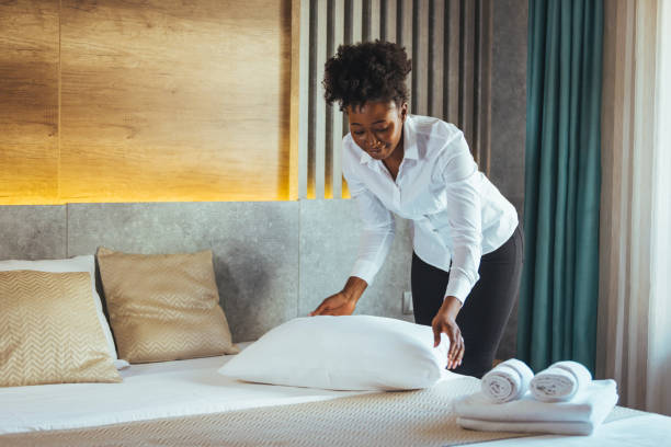 istock Young chambermaid with pillow in hotel room. 1366601894